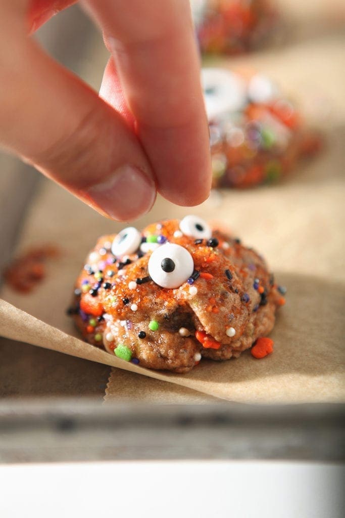 A woman presses a candy eyeball into a cookie