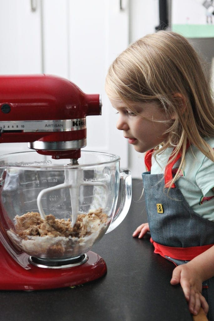 A girl watches as cookie dough ingredients mix