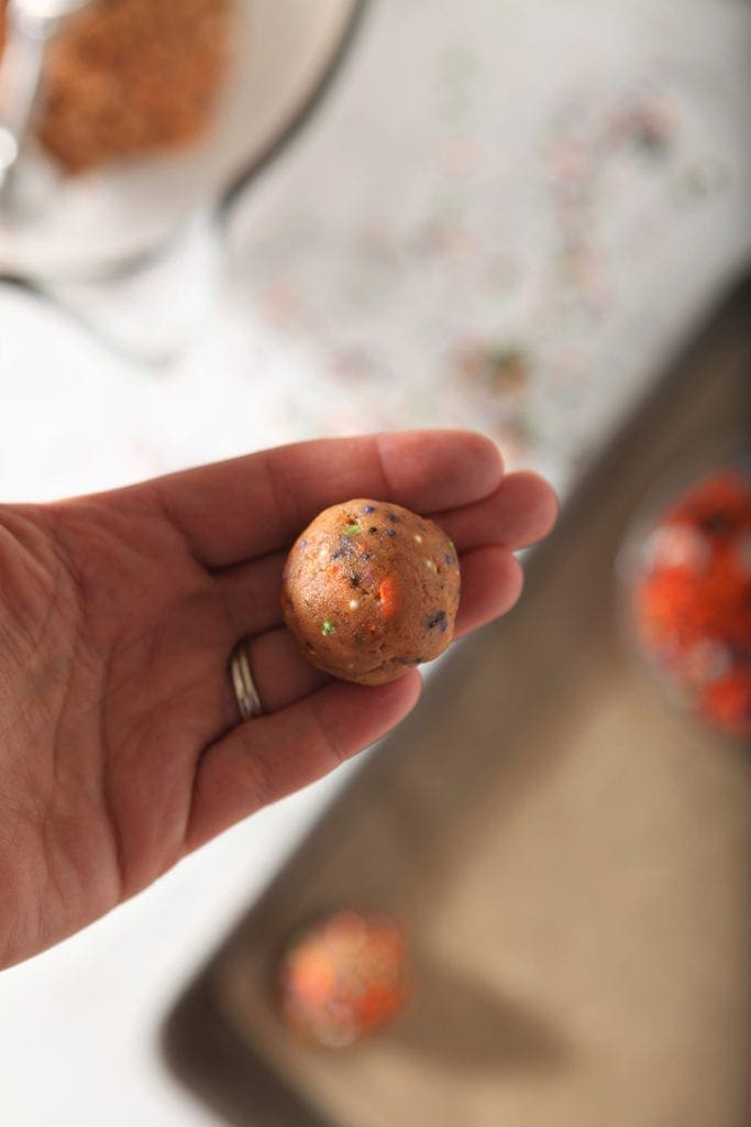 A woman holds a cookie dough ball in her hands