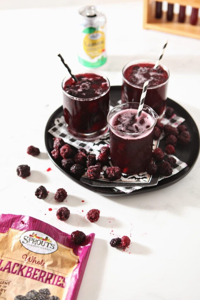 Three glasses of Fizzy Potion Punch sit on a platter, surrounded by the ingredients