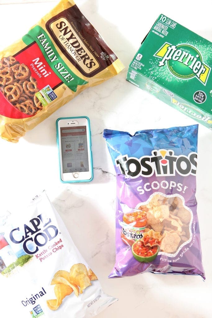 Bags of chips surround a phone, which shows the Tom Thumb app