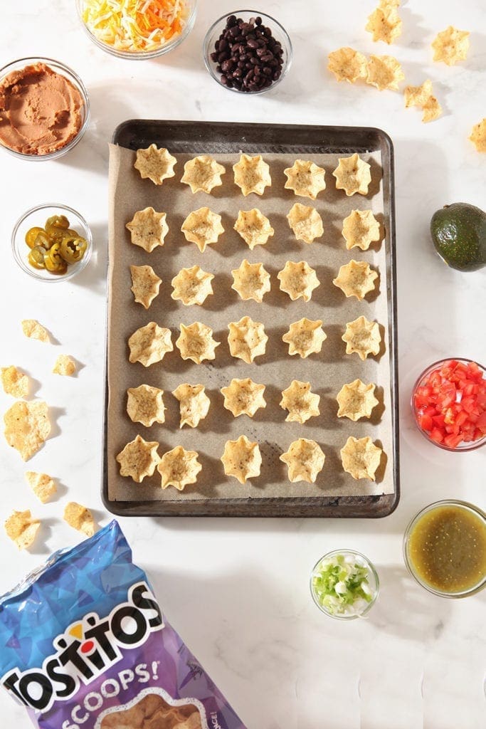 Tortilla chips are laid out on a baking sheet before being filled with nacho ingredients