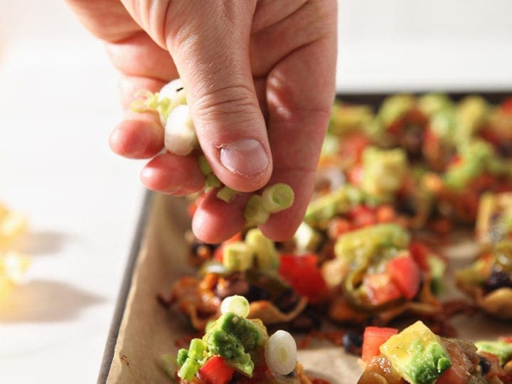 green onions are sprinkled on top of baked taco cups before serving