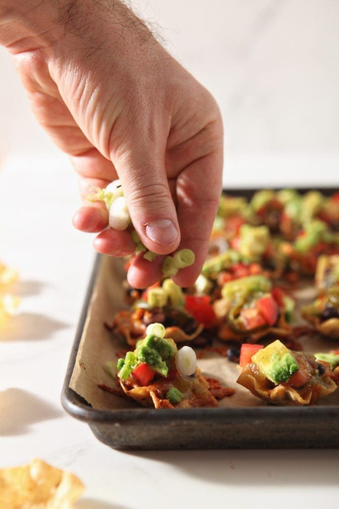 green onions are sprinkled on top of baked taco cups before serving