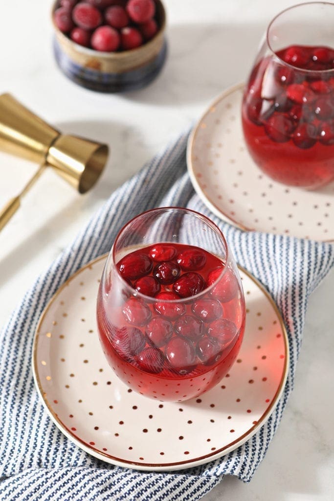 Glasses of Cranberry Sangria sit on golden plates, ready for sipping