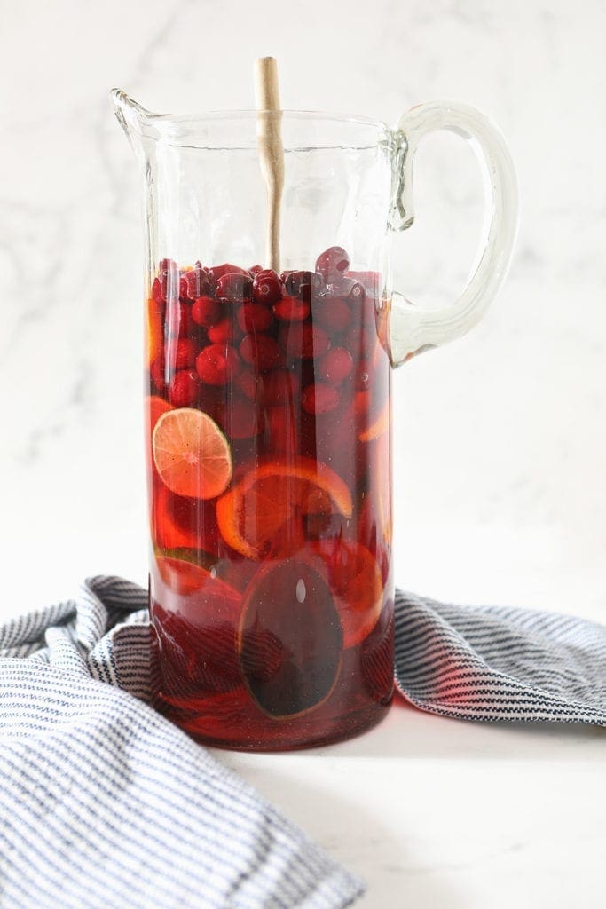 A wooden spoon stirs a pitcher of sangria, before it infuses