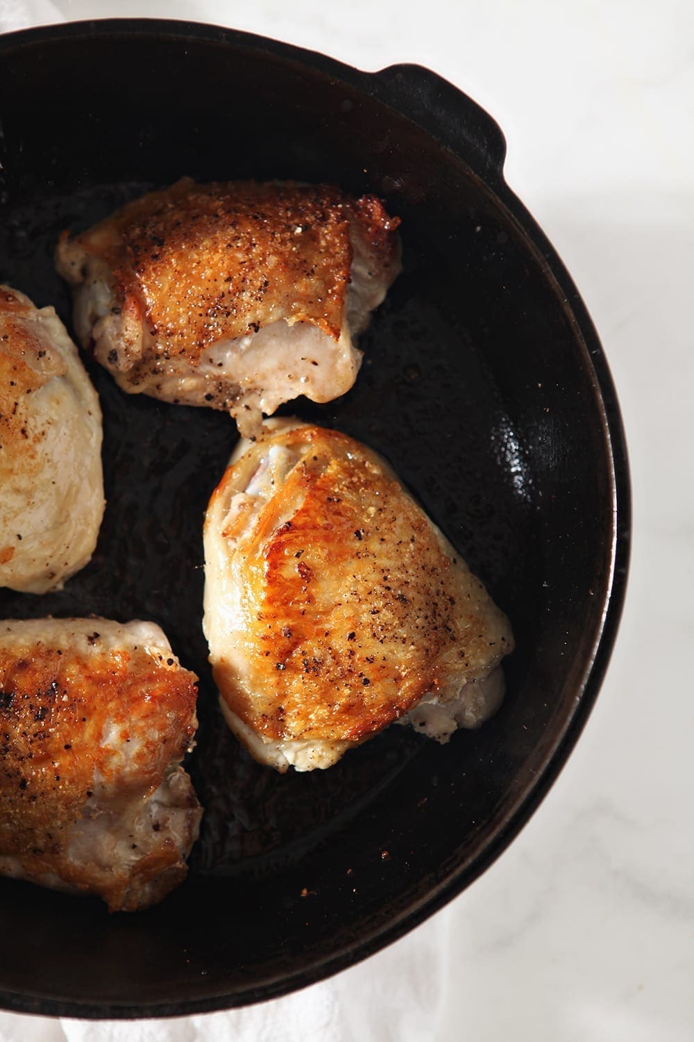 Seared bone-in, skin-on chicken thighs, in a cast iron skillet