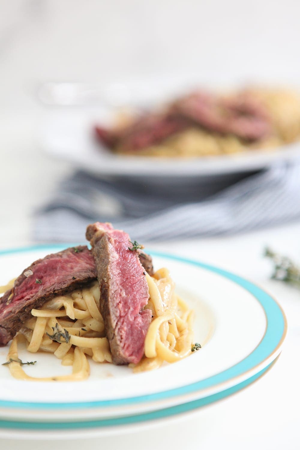 Close up of sliced rare steak over French Onion Pasta