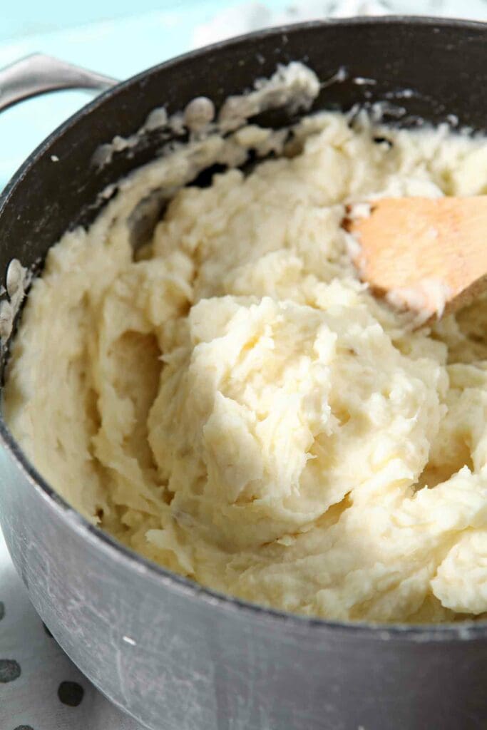 Garlic Parmesan Mashed Potato Casserole is shown in a pot, just after mixing in all the ingredients, and before it is transferred to a baking dish to cook in the oven with additional cheese