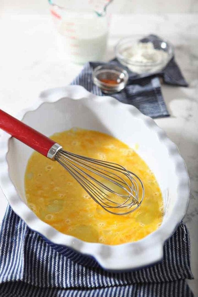 A whisk sits in a dish, after whisking eggs