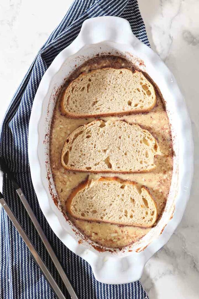 Overhead of sliced bread soaks in the egg-milk-yogurt mixture