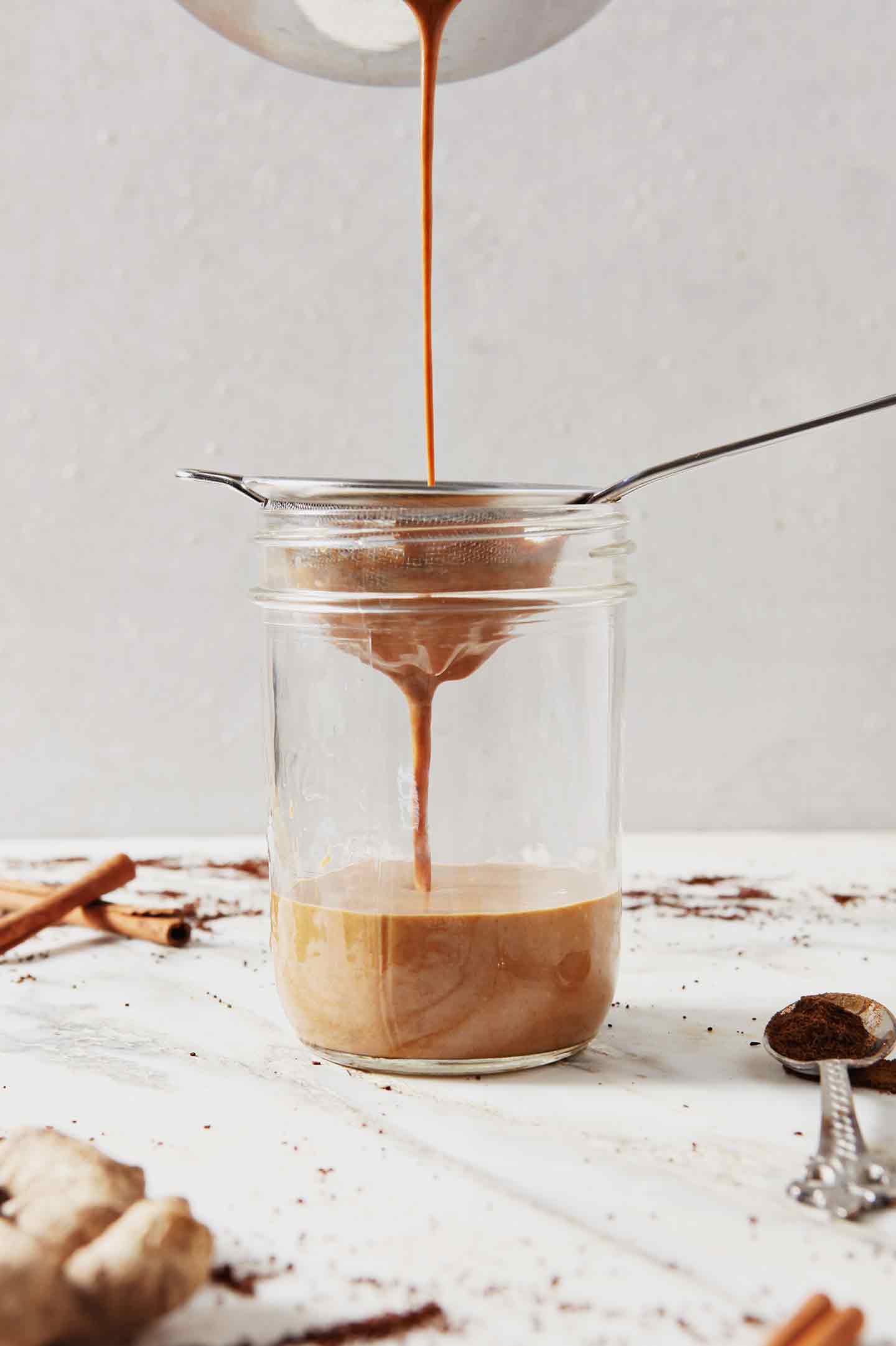 Gingerbread Coffee Creamer is poured through a fine mesh strainer into a mason jar