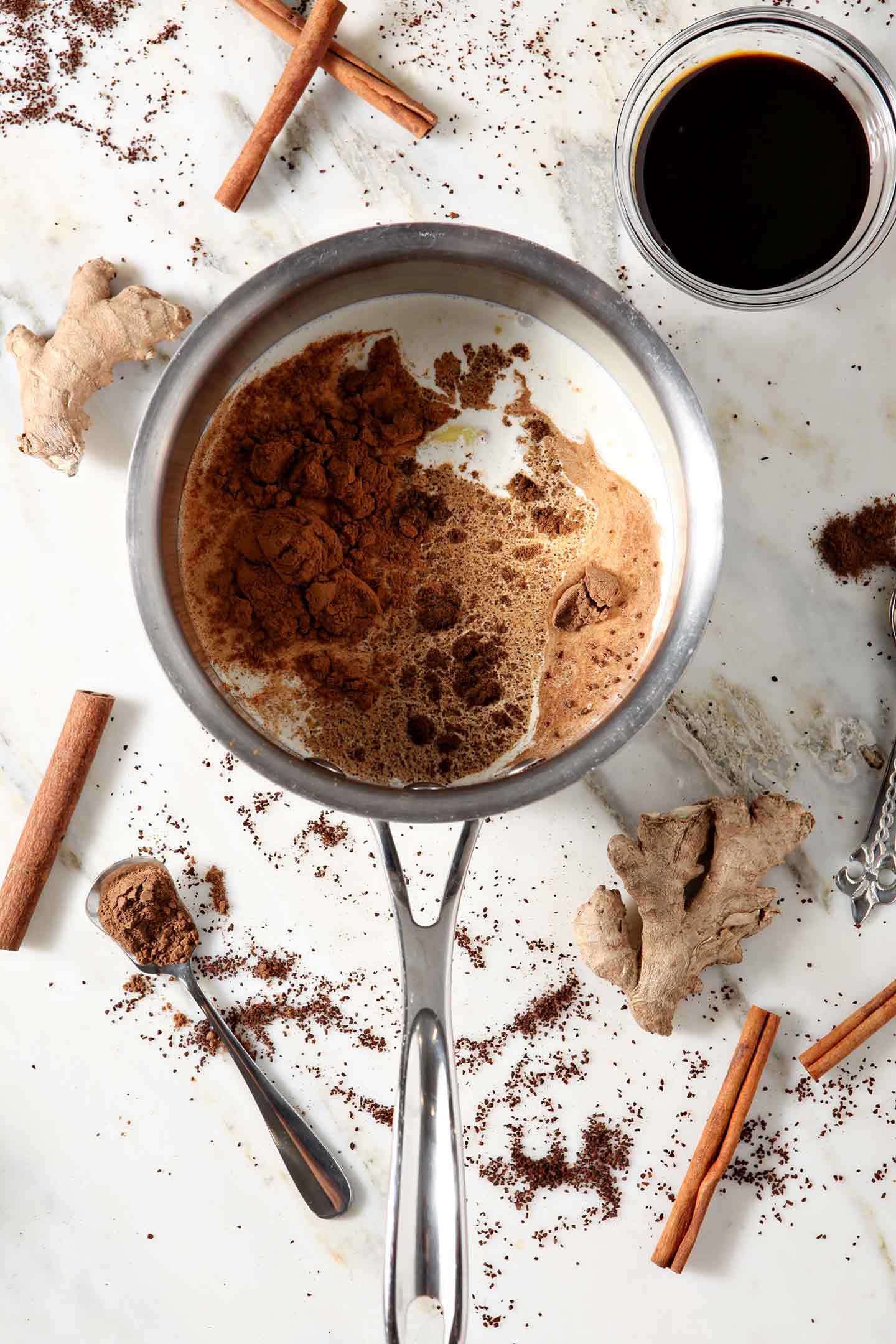 Ingredients for the creamer in a saucepan, from above, surrounded by the ingredients on marble