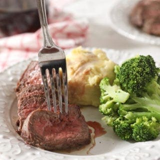 A fork sticks a sliced piece of steak before lifting it from the plate