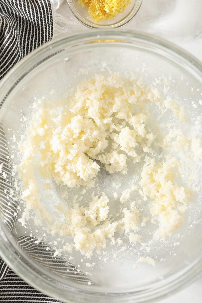 Sugar and butter are creamed together in a clear glass bowl