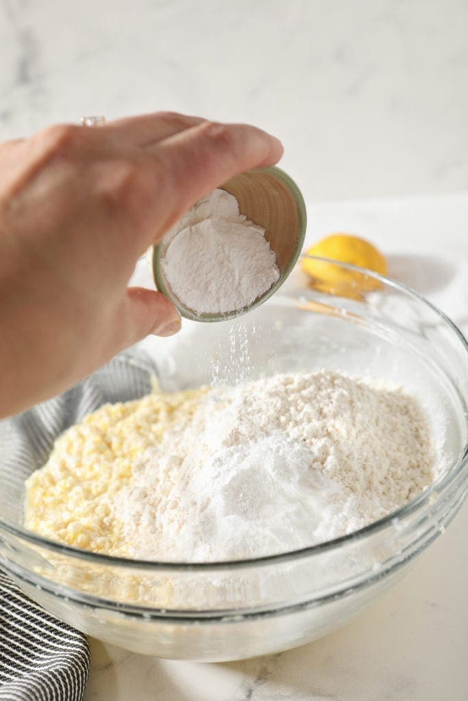 Baking powder is sprinkled into a bowl containing cookie dough, before mixing