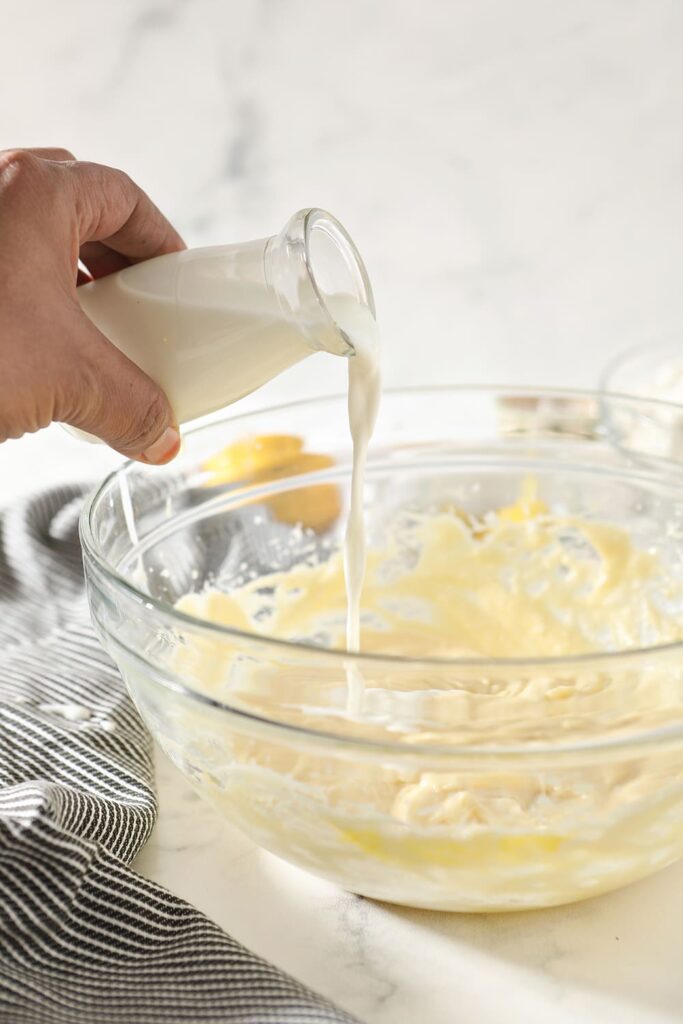 Milk is poured into a bowl of cookie batter