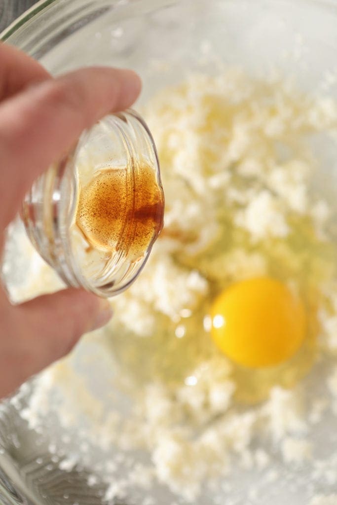 Vanilla extract is poured into a bowl holding cookie ingredients