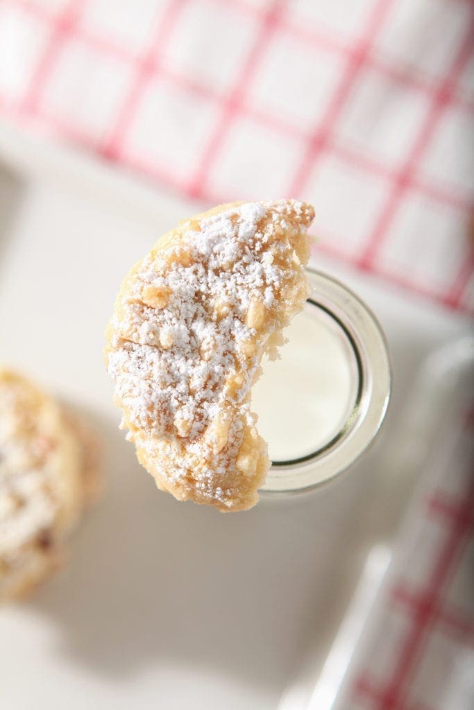 A half eaten cookie sits atop a bottle of milk