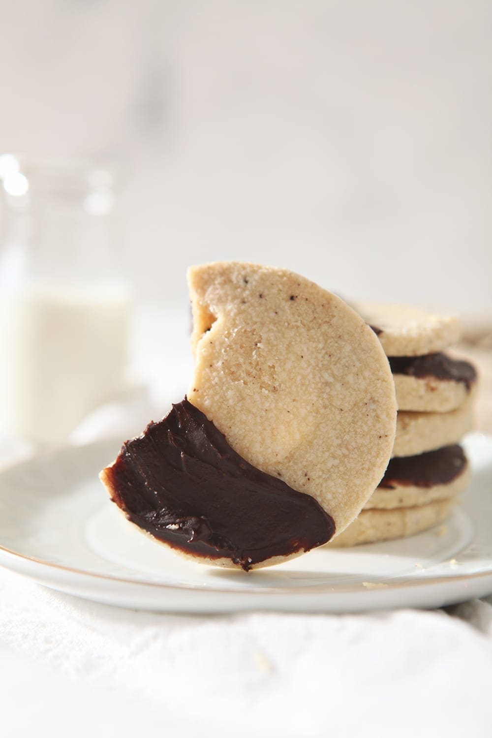 A Shortbread Brown Butter Cookie with a bite taken out of it on a white plate