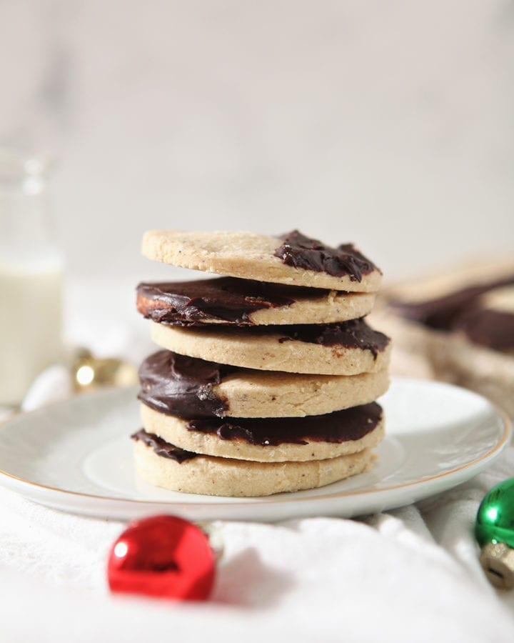 A stack of brown butter shortbread cookies on a white plate with a glass of milk