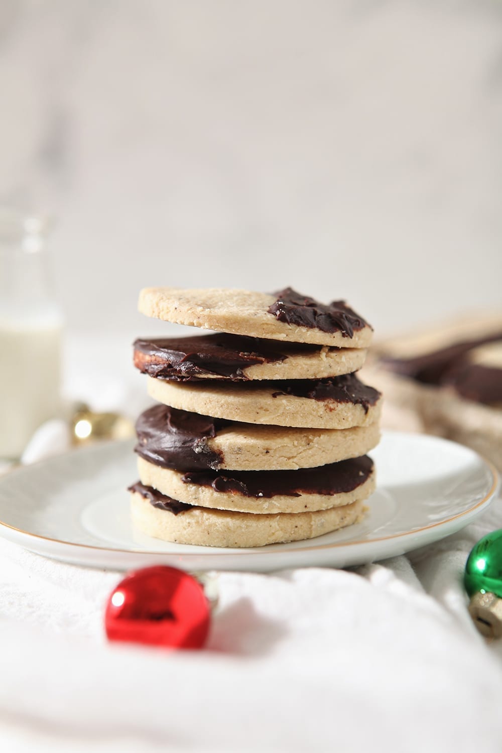 A stack of brown butter shortbread cookies on a white plate with a glass of milk