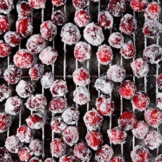 Sugared cranberries sit on a cooling rack, after chilling in the fridge