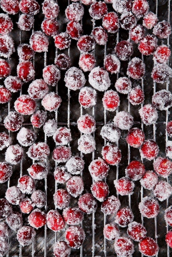 Sugared cranberries sit on a cooling rack, after chilling in the fridge