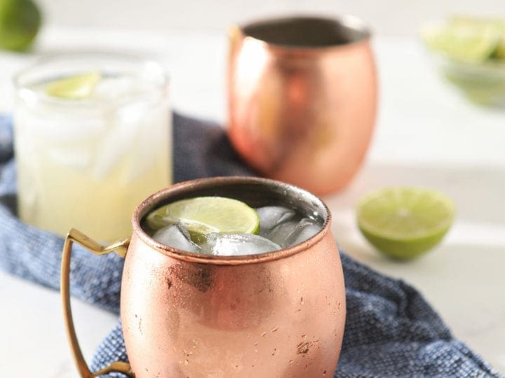 Three glasses holding Classic Moscow Mule cocktails are shown on a blue towel
