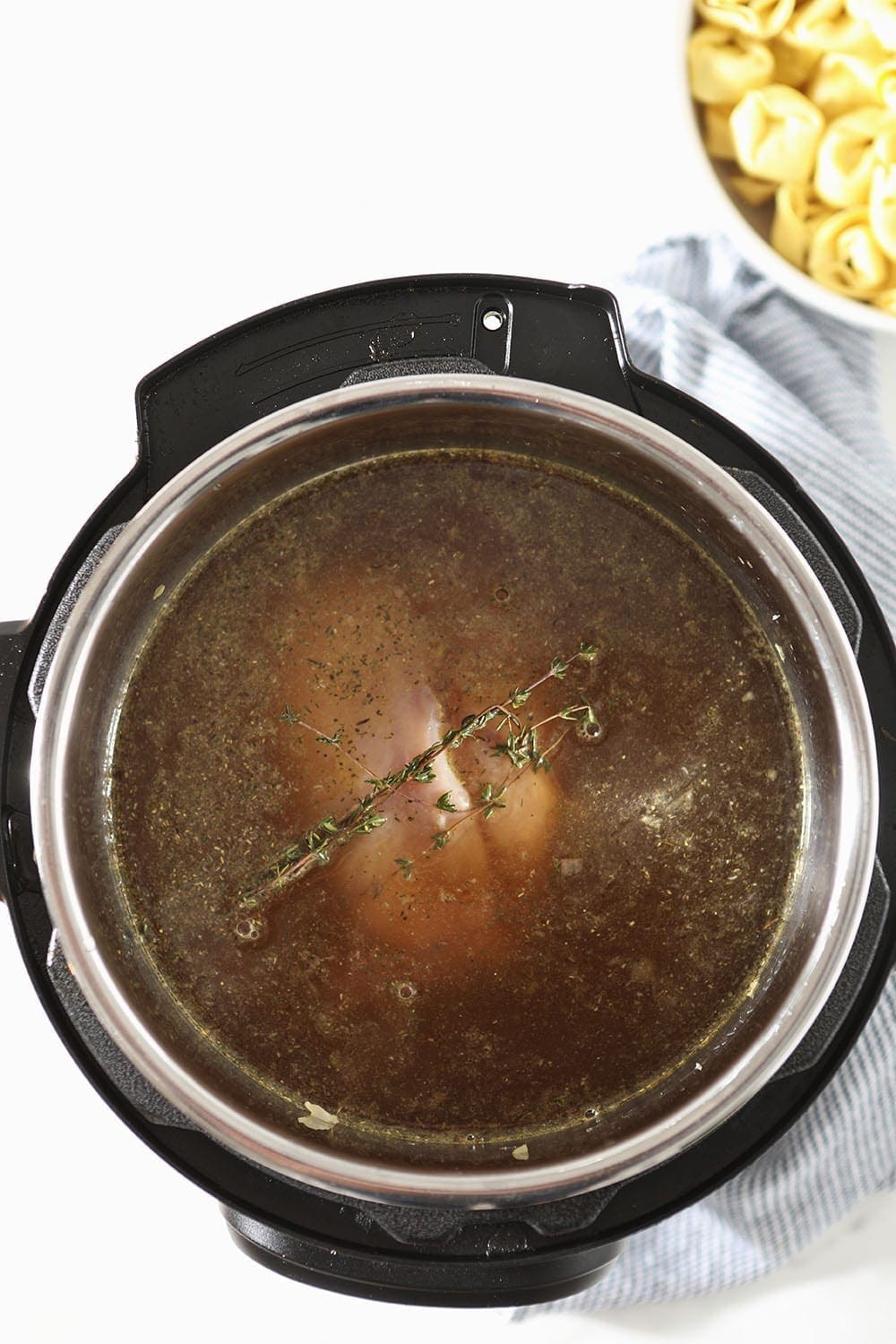 Liquid is poured on top of Chicken Tortellini Soup, before cooking