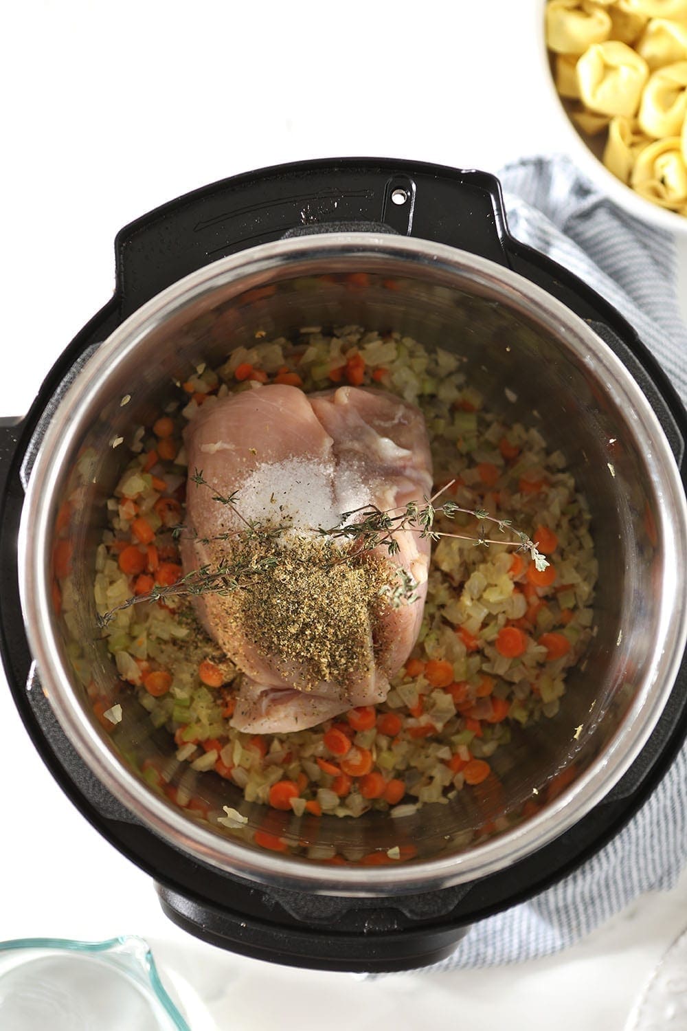 Chicken, veggies and seasonings are laid in the INstant Pot, before cooking