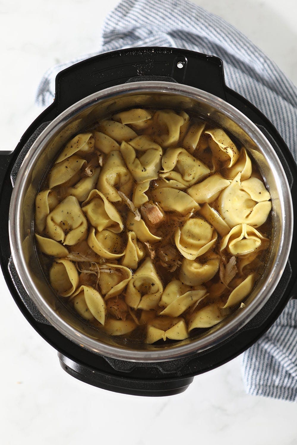 Tortellini is added to the slow cooker, from above