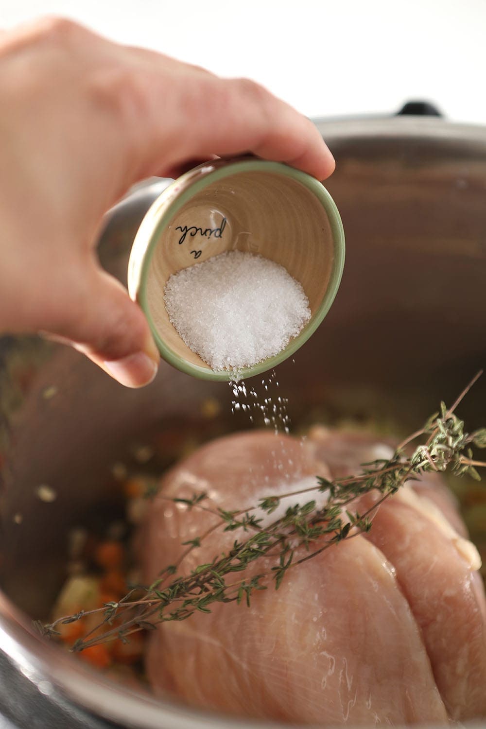 Salt is sprinkled on top of the chicken and the rest of the soup ingredients