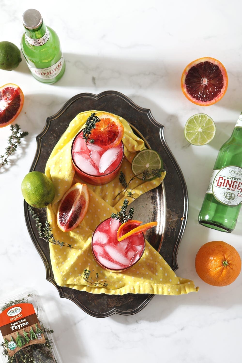 Overhead of Blood Orange Mocktail Mules on a silver platter, surrounded by the ingredients