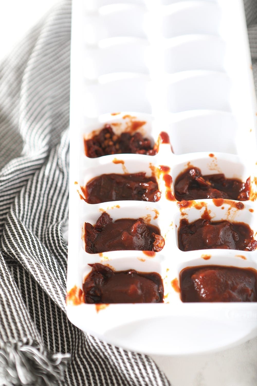 Chopped chipotles en adobo are shown in an ice cube tray, before freezing and storing in the freezer