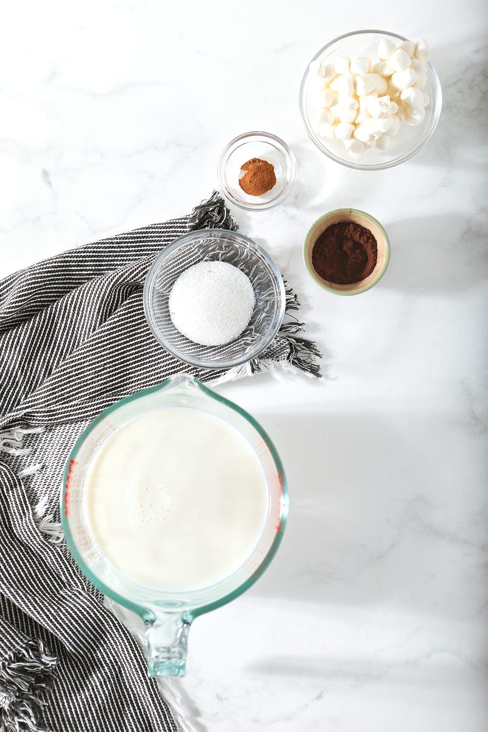 Ingredients for hot cocoa are shown from above on a gray striped napkin