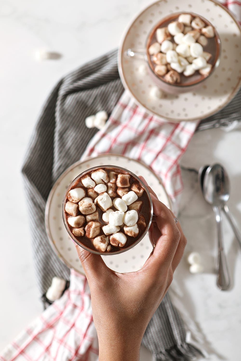 A woman holds a mug of Gourmet Hot Chocolate, from above