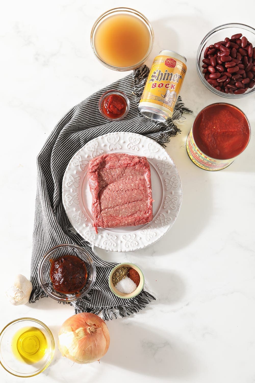 Ingredients for chili are shown on a marble counter, all in separate bowls