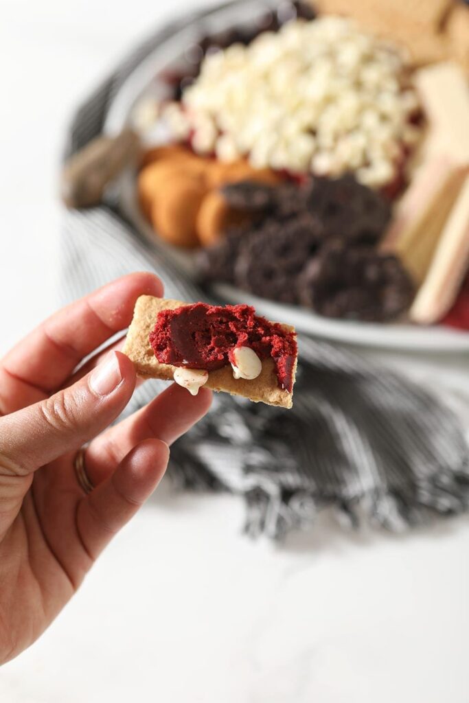 The red velvet cheese ball is smeared on a piece of Graham cracker, before consuming