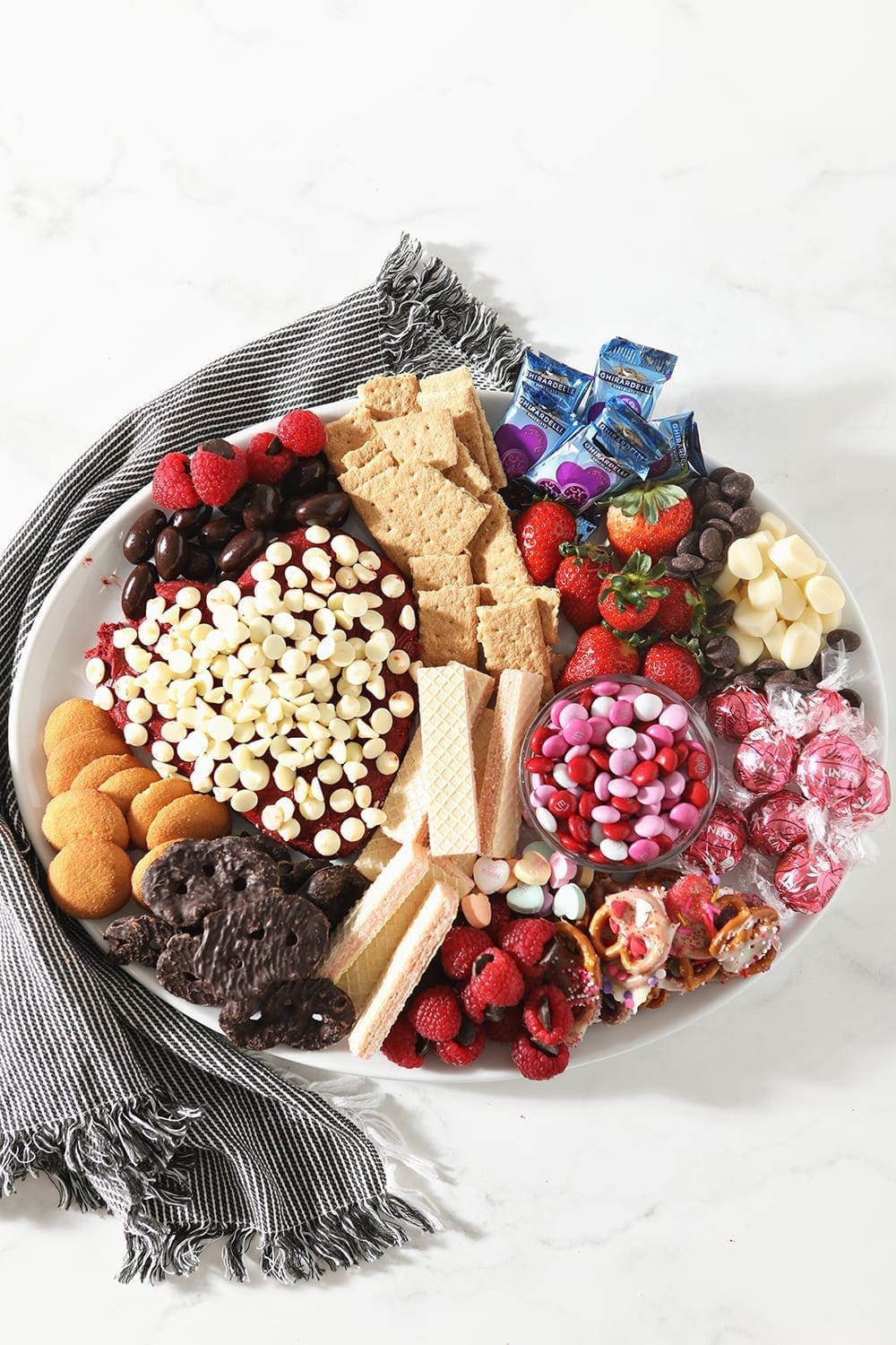 Overhead image of a white platter holding the Dessert Board, sitting on a blue striped napkin