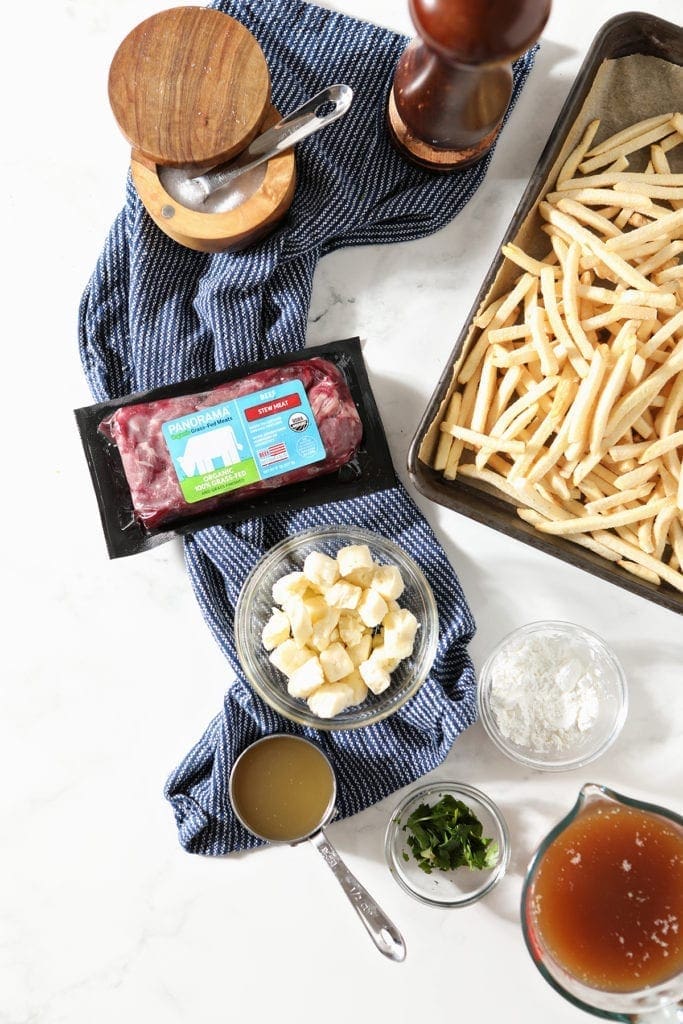 Poutine gravy and fries ingredients in bowls on marble 