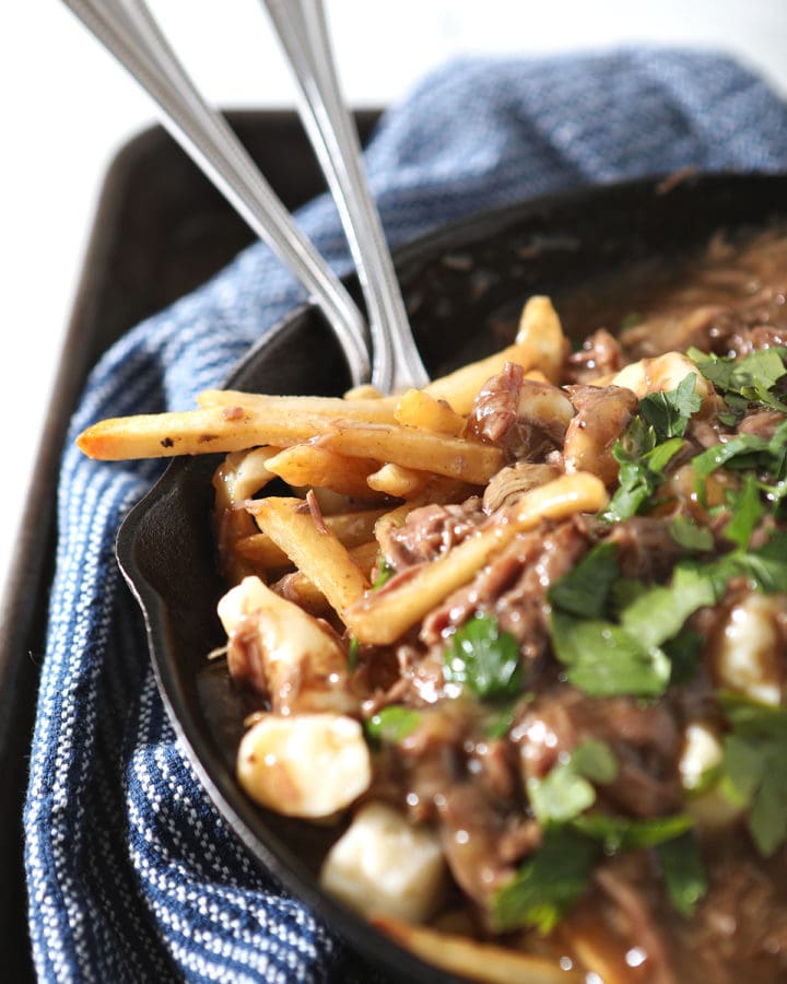 Close up of Beefy Poutine Fries and Gravy with forks in a skillet