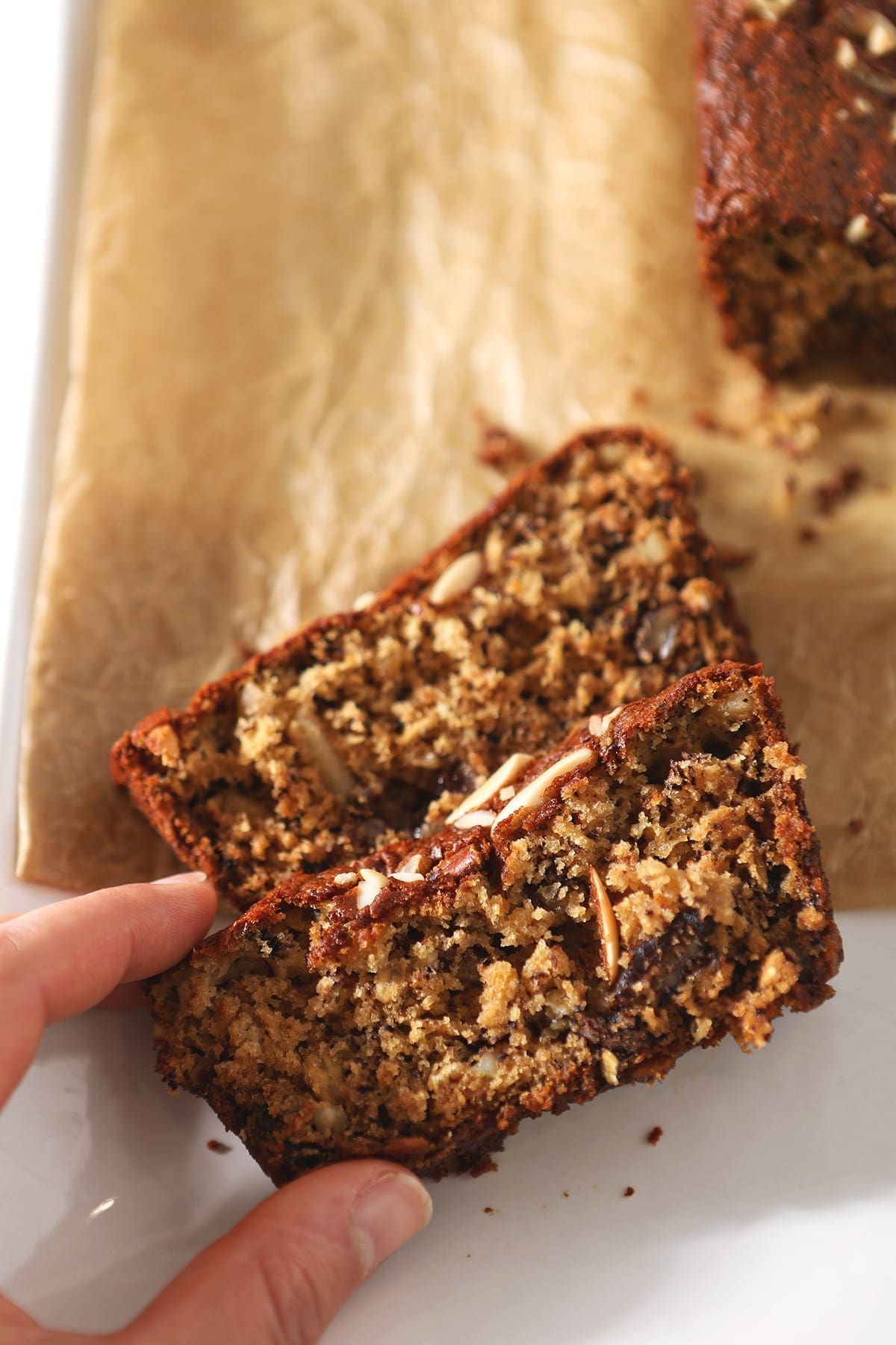 A woman grabs a slice of Eggless Banana Bread, close up