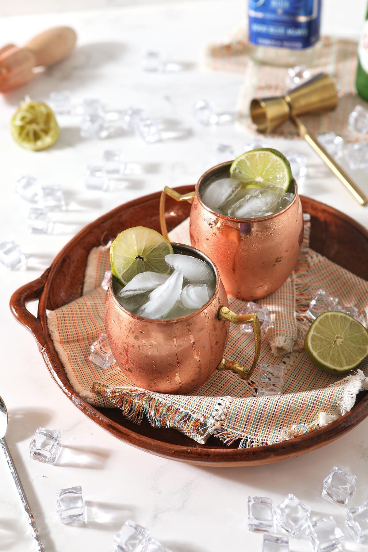 A brown tray holds two copper mugs of Mexican Mules, with ice and lime wedges around them