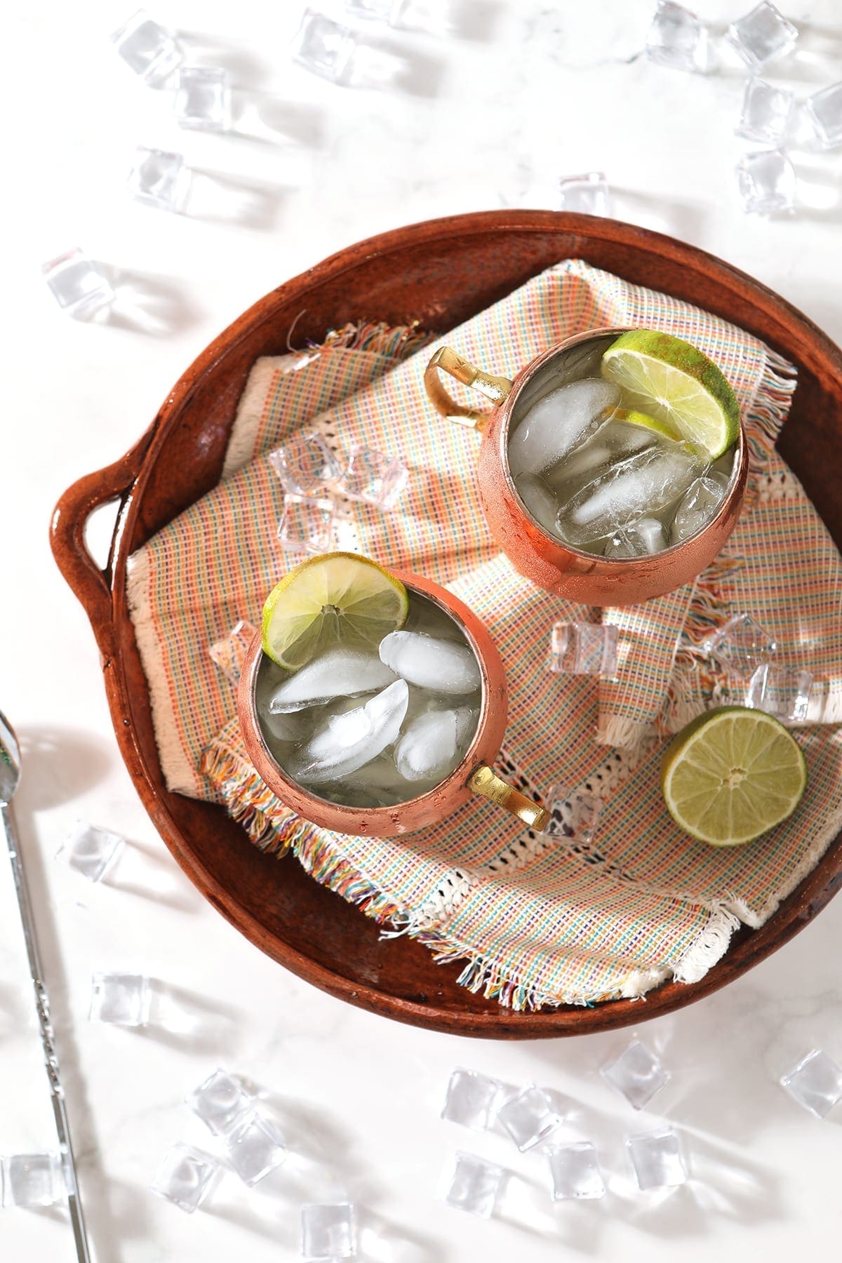 Overhead of a platter holding two Mexican Mules in copper mugs, with lime garnishes and ice