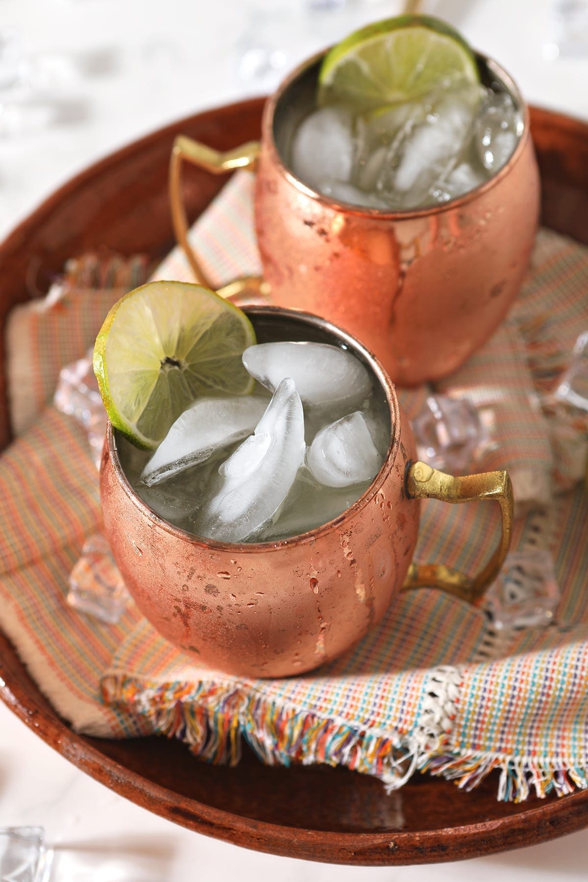 Overhead of two copper mule mugs holding liquor, on a platter