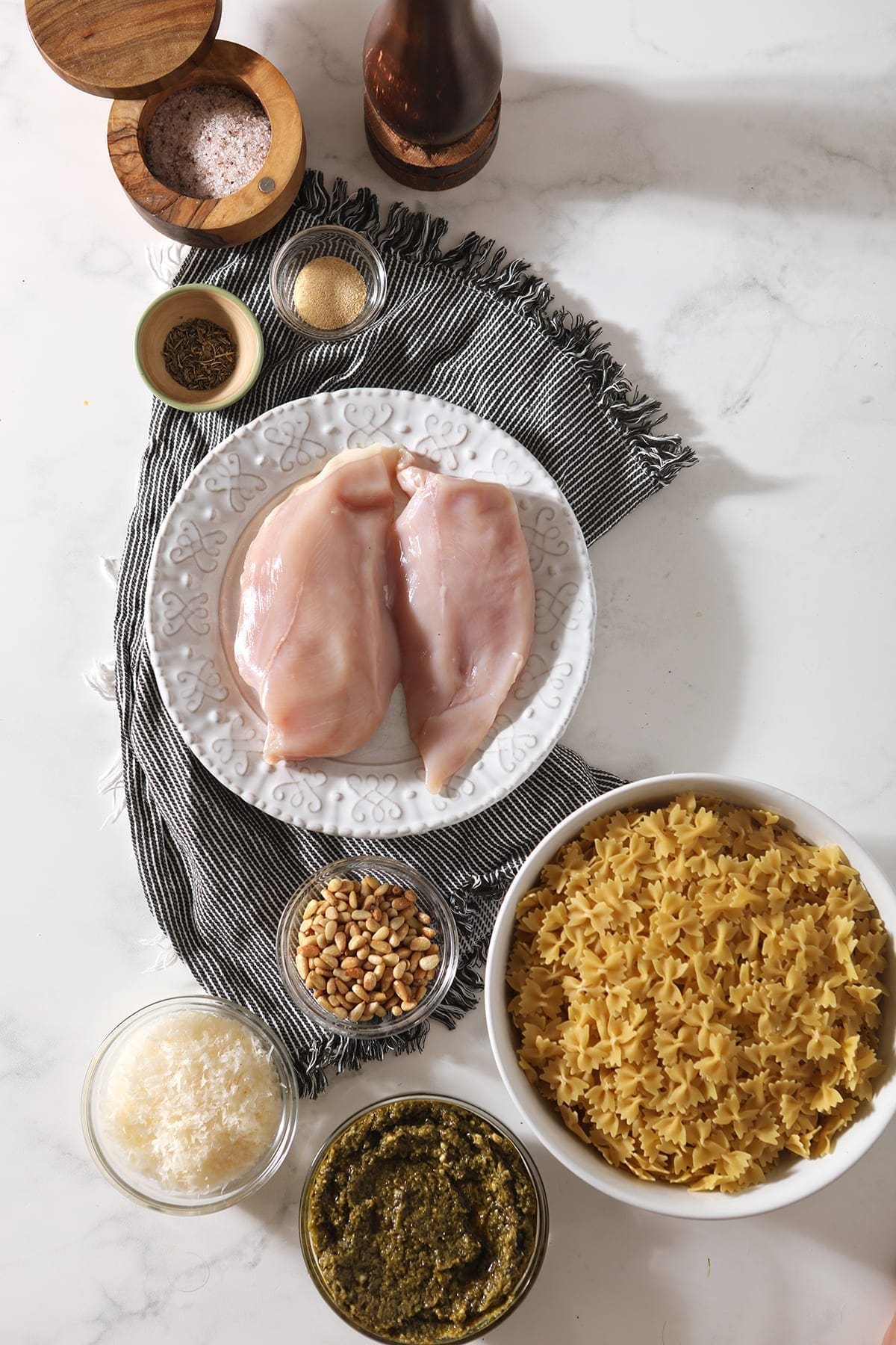 Ingredients in bowls and platters are laid out on a marble background before cooking