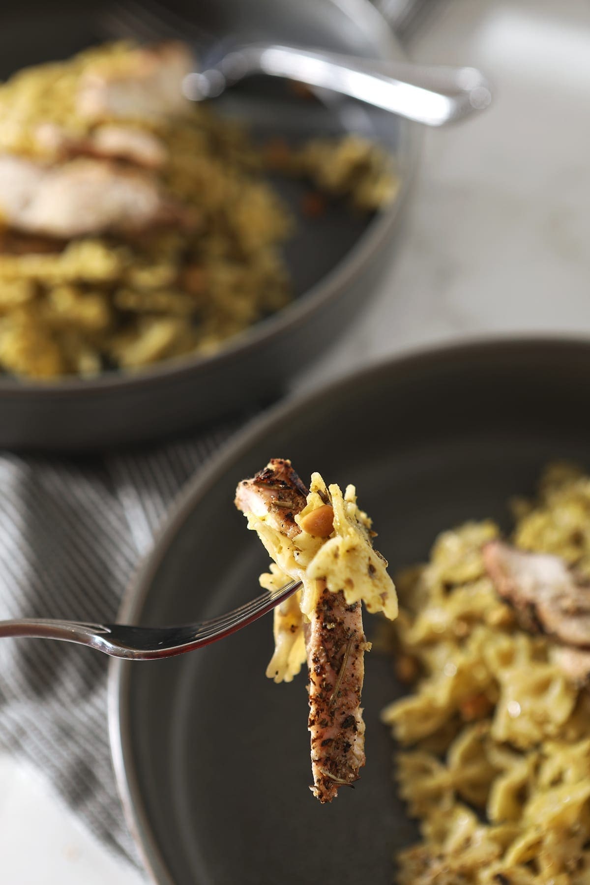 A fork holds a bite of Chicken Pesto Pasta, from above