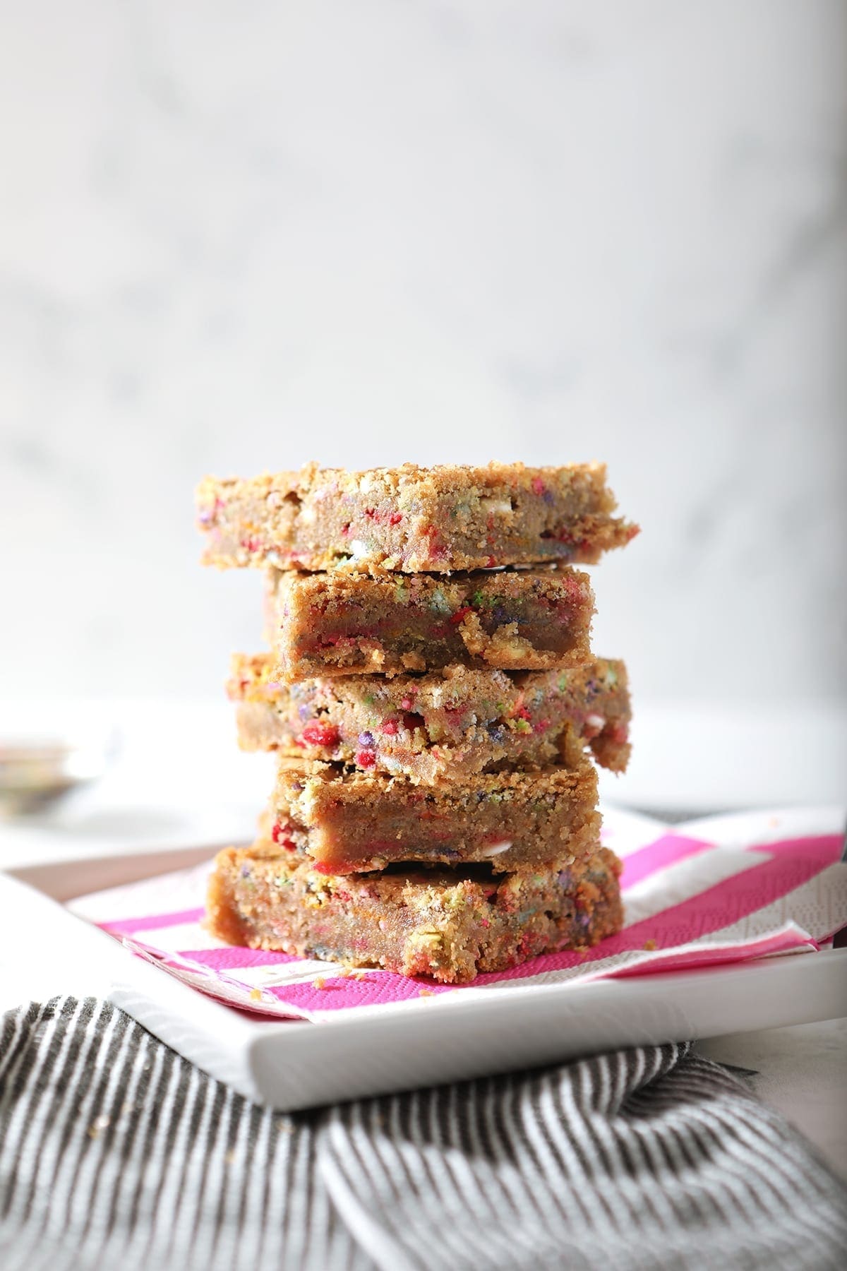 A stack of five cookie bars on striped pink and white napkins