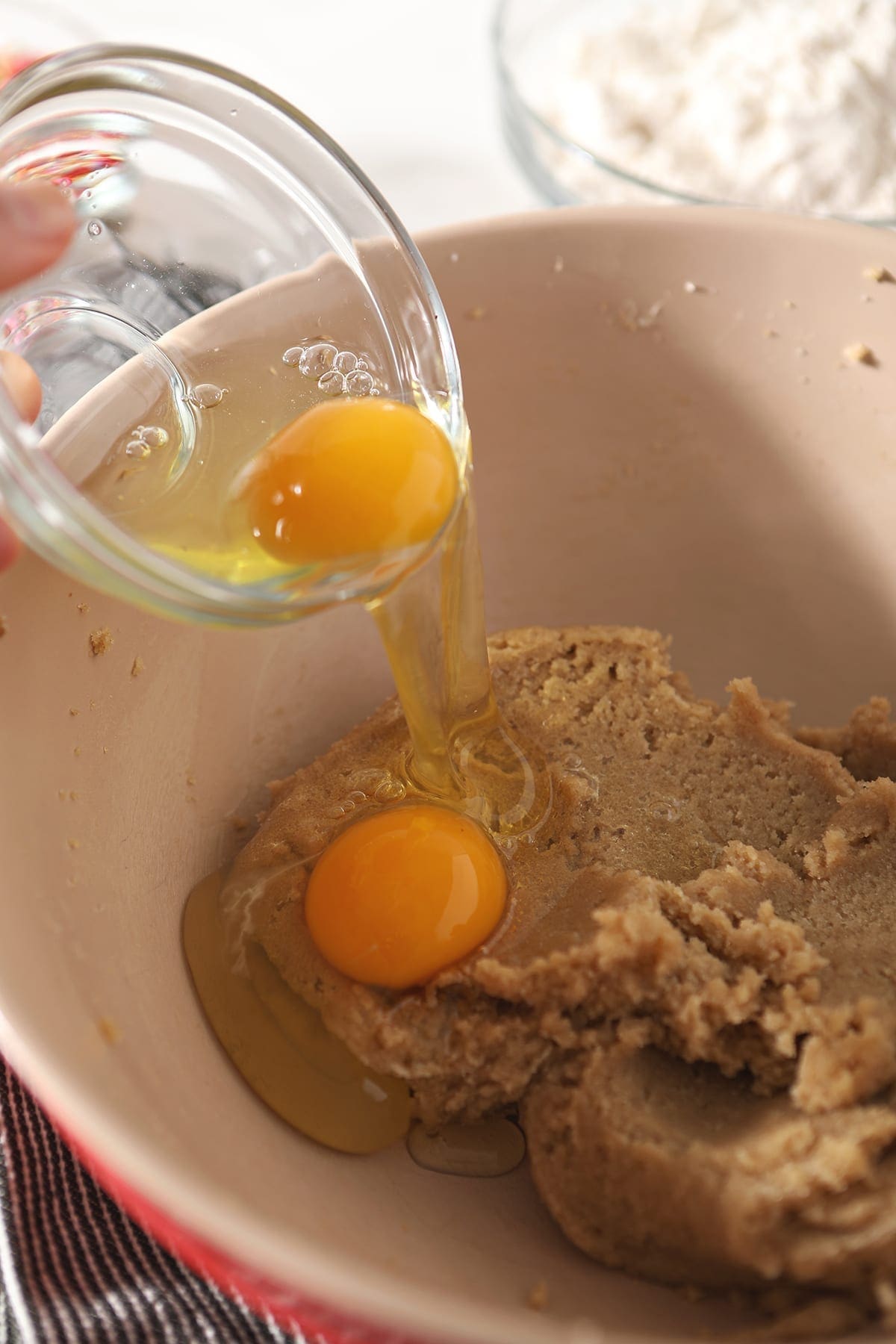 Eggs are dropped into a bowl of cookie ingredients